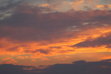 Evening sky in picturesque clouds, illuminated by the rays of the setting sun. Evening glow.