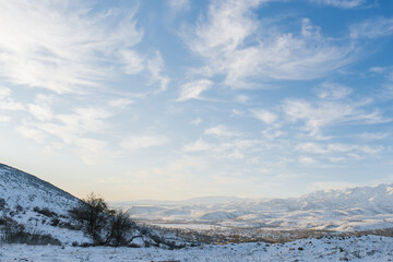 Fototapeta na wymiar Beautiful clouds against the blue sky over the Tien Shan mountains in winter in Uzbekistan