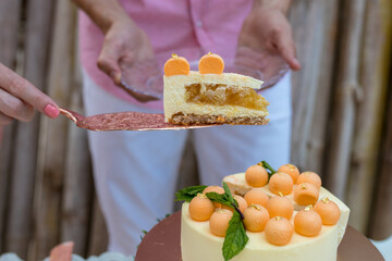 Close up view of bride and groom cutting yellow wedding cake with orange mousse balls on the top...