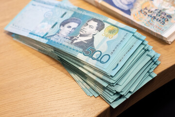 Full pack of Dominican Republic 500 peso bank notes on wooden table. Travel currency exchange theme.