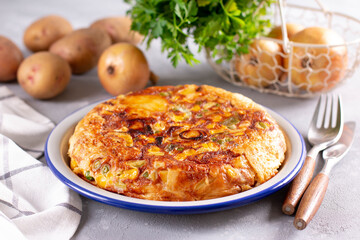 Frittata of eggs, potatoes, paprika, parsley, green peas, onions, cheese on a plate