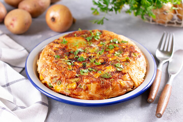 Frittata of eggs, potatoes, paprika, parsley, green peas, onions, cheese on a plate