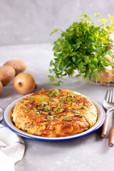 Frittata of eggs, potatoes, paprika, parsley, green peas, onions, cheese on a plate