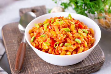 Stewed red lentils with vegetables in a white bowl on a light background. Bright, tasty, spicy food.