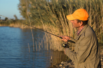 Fisherman standing on the riverside and trying to catch a fish. Sport, recreation, lifestyle.