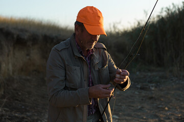 Fishing rod wheel closeup, man fishing with a beautiful sunset.