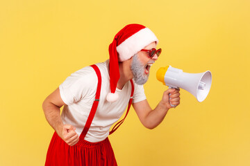 Profile portrait excited nervous grey bearded man in santa claus hat screaming holding loudspeaker...