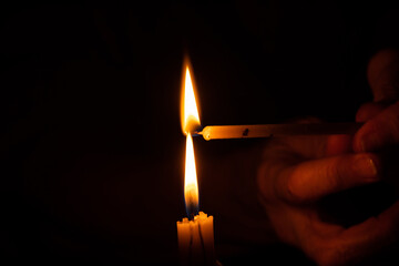 old woman's hands and candle flame in the dark, mourning, candle in the dark