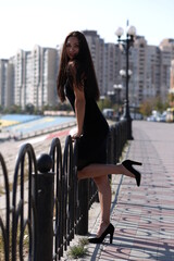 Naklejka premium young girl in a black dress walking in the city