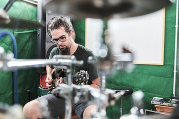 Guitarist playing guitar while sitting on the chair.