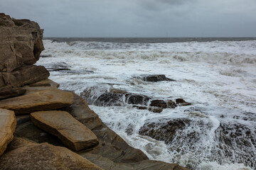 Rough, stormy, seas and waves on rock at Seaton Sluice, Northumberland, England, UK.