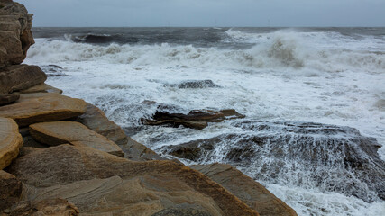 Rough, stormy, seas and waves on rock at Seaton Sluice, Northumberland, England, UK.
