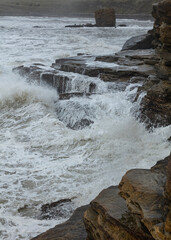 Rough, stormy, seas and waves on rock at Seaton Sluice, Northumberland, England, UK.