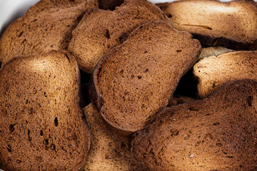 The texture of toasted pieces of bread. Croutons on a white background. Dark dry bread.
