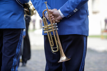 Details with the hands of a military fanfare member holding a brass wind musical instrument.