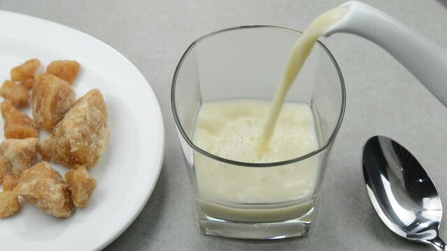 Serving hot jaggery milk in a glass cup