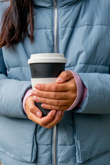 reusable Cup of coffee to take away in the hands of a girl. Keep your hands warm in the cold