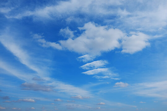 White cirrus clouds on a background of dark blue sky. The cloud resembles a flying angel.