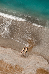 Aerial view of a woman in the Mediterranean Sea in Turkey. Beautiful summer landscape with a girl, clear azure water, waves and sandy beach on a sunny day. Top view from a flying drone.