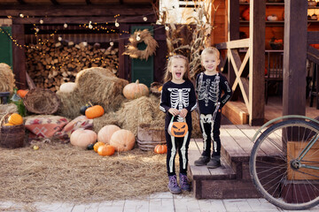 Siblings in the yard are celebrating Halloween. Children are happy cute beautiful wearing skeletons. Decoration for the holiday on October 31 eve. Childhood joy masquerade. autumn 2020. best Friends 