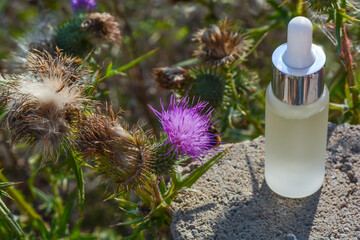 burdock oil on a natural background of greenery of flowers and branches burdock oil in blur