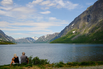 Fototapeta na wymiar An elderly couple admires and enjoys the peaceful Norwegian nature on a sunny summer-day