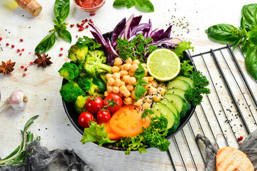 Vegan Buddha bowl: chickpeas, broccoli, tomatoes and cucumber on a black stone plate. Food. Top view. Free space for your text.