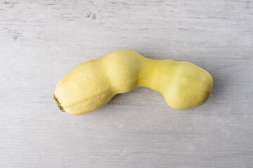 Ugly vegetable marrow, on a gray wooden background. Ugly food concept, top view, copy space.