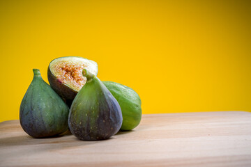 Fresh figs on a wooden table with yellow background. Free space for text. close-up shot