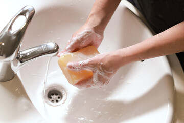 manos lavandose con jabón en un lavabo para evitar contagios covid