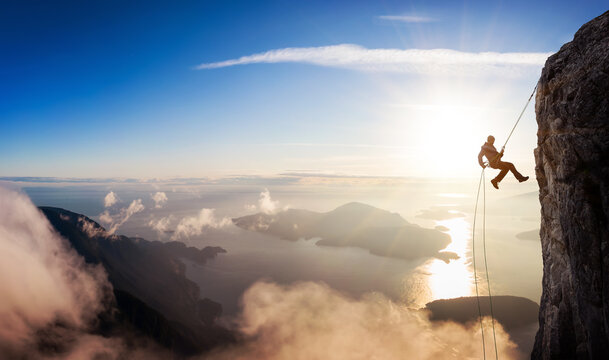 Epic Adventurous Extreme Sport Composite of Rock Climbing Man Rappelling from a Cliff. Mountain Landscape Background from British Columbia, Canada. Concept: Explore, Hike, Adventure, Lifestyle
