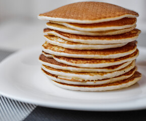 A stack of pancakes is on a white plate
