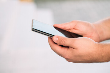 male hands holding a modern phone mock-up for your text message or information content, on the street