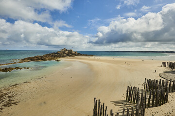 Wooden Poles et Fort National on the beach at low tide in Saint Malo, Brittany, France