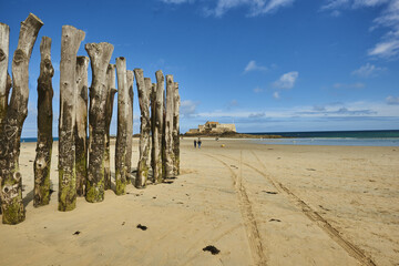 Wooden Poles et Fort National on the beach at low tide in Saint Malo, Brittany, France