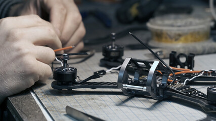 Guy soldering drone FPV wires. Frontframe view