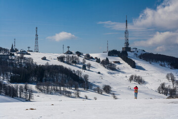 Wanderin in roter Jacke schaut in die Ferne auf einen lost Place, Rumänien, Winter