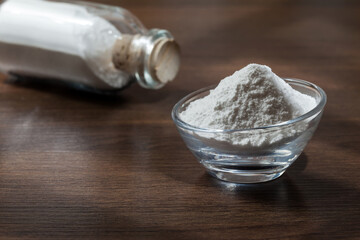 Baking soda (sodium bicarbonate) on dark wooden background.