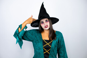 Woman wearing witch costume over isolated white background Shooting and killing oneself pointing hand and fingers to head like gun, suicide gesture.