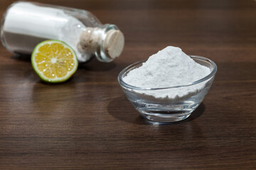 Baking soda - sodium bicarbonate and lemon; on dark wooden background.