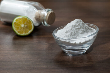 Baking soda - sodium bicarbonate and lemon; on dark wooden background.