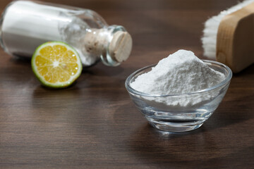 Baking soda - sodium bicarbonate and lemon; on dark wooden background.