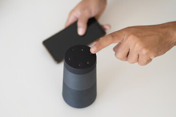 hands of a man connecting a phone with wireless speakers