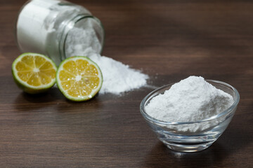 Baking soda - sodium bicarbonate and lemon; on dark wooden background.