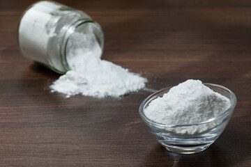 Baking soda (sodium bicarbonate) on dark wooden background.