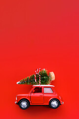 Little red toy car and Christmas tree on a red background
