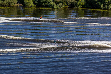 Two athletes on the boards towed behind speed boats meet oncoming courses. Athlete water skiing and having fun. Speed boat for Surfing the Wakeboard. Water skiing on lake behind a boat. Top view