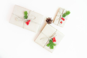 Fototapeta na wymiar Christmas eco flat lay: gifts wrapped in craft paper, spruce branches and red berries as a decoration. Sustainability concept.