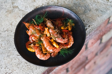 Thai fried shrimps in a black plate on a stone surface. Traditional street food