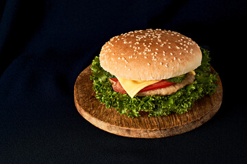 Delicious classic burger on wooden cutting board isolated on black background